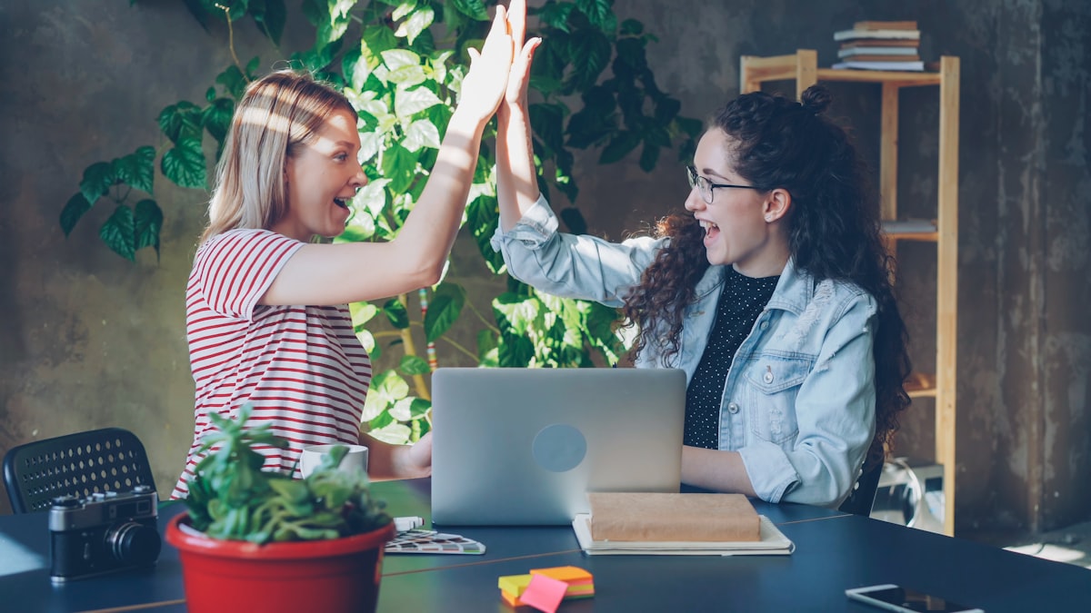 Two team members celebrating a quick win with a high five in the office, representing the early victories a new CTO should aim for