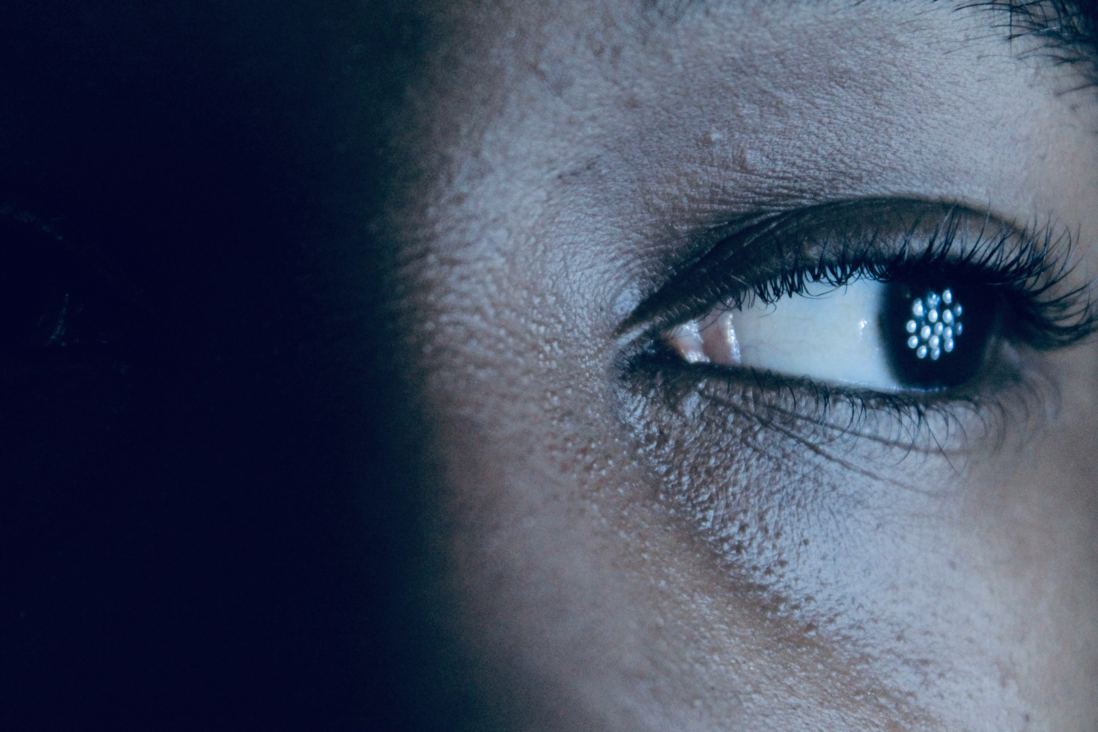 Close-up of a human eye reflecting digital patterns, representing AI-powered surveillance and autonomous code analysis