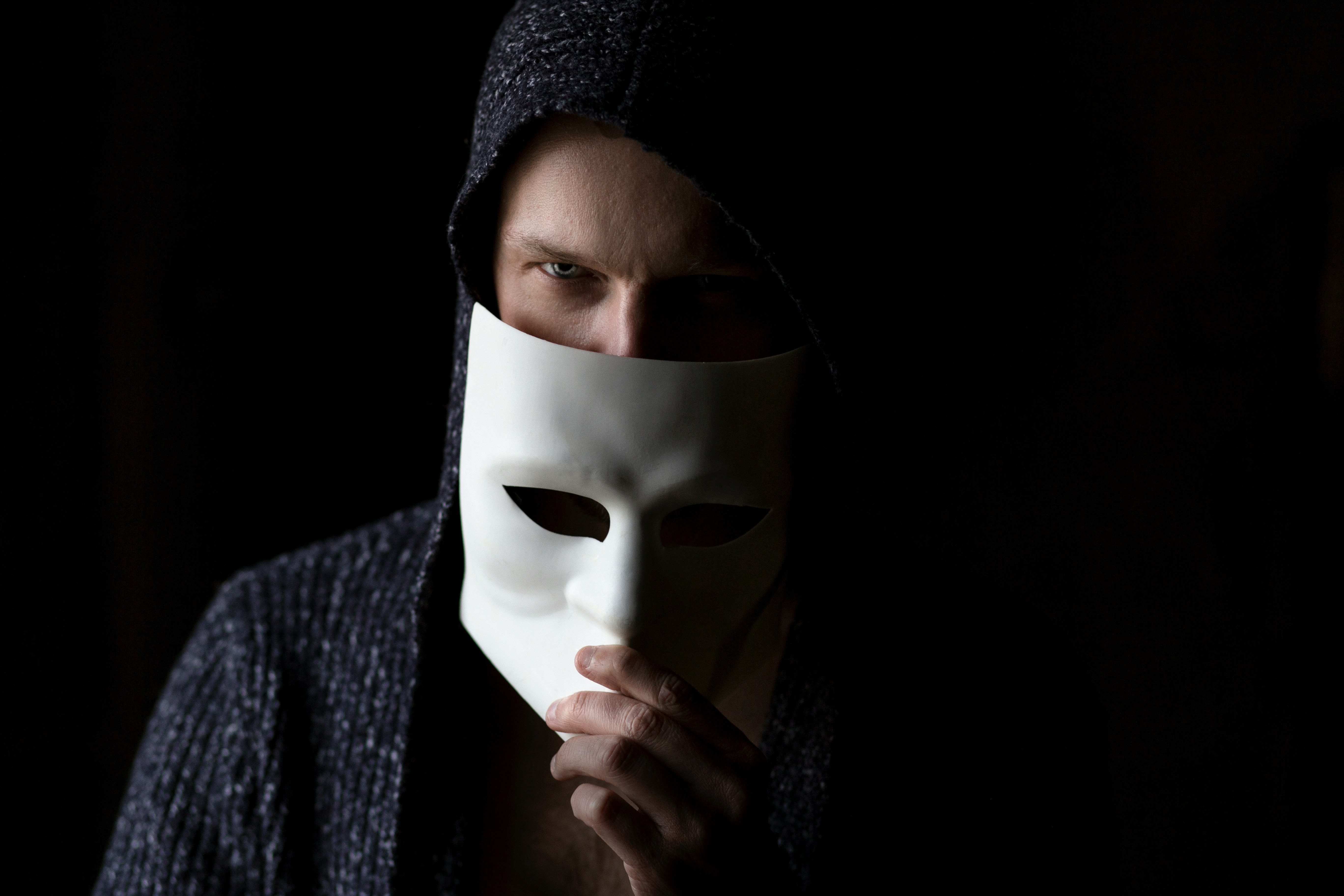 A masked figure in dark clothing, representing the deceptive nature of social engineering attacks