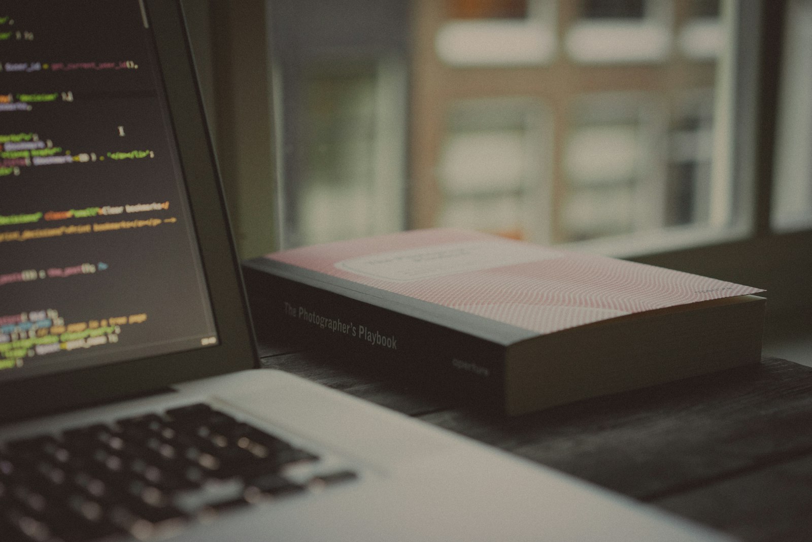 An open programming book next to a laptop