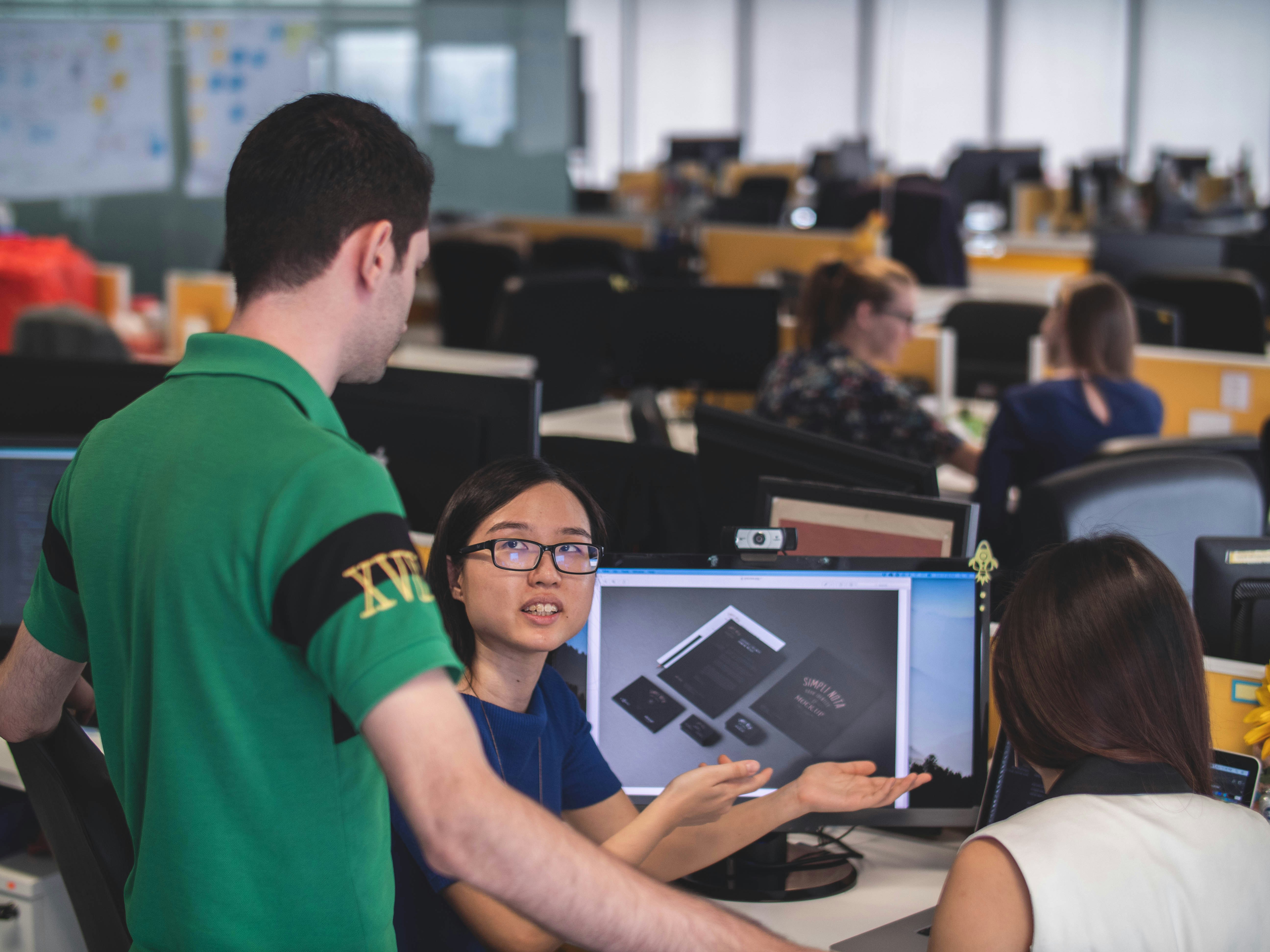 Engineering team collaborating around a computer screen, discussing code together